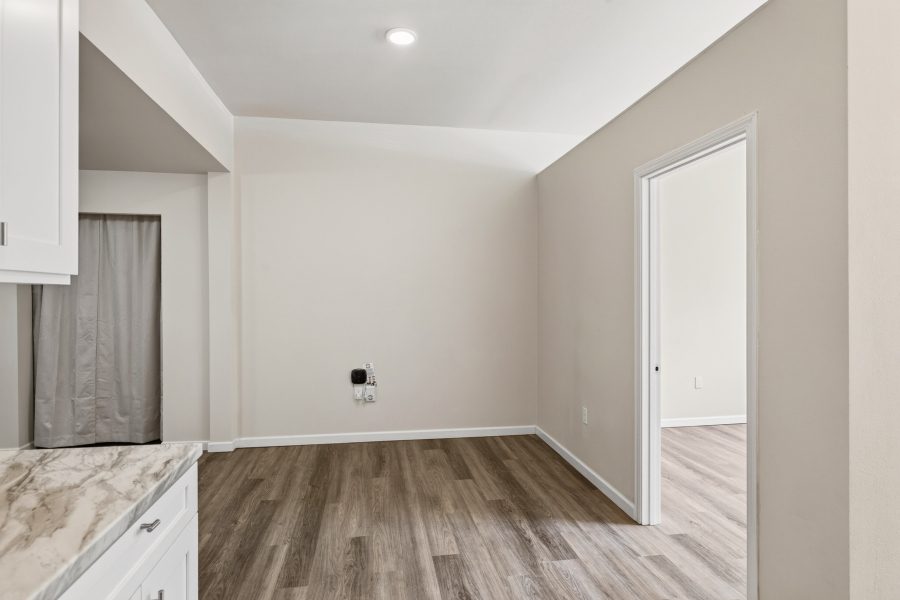 Unit 2 dining area, unfurnished, with a curtained laundry alcove and a doorway to the bedroom