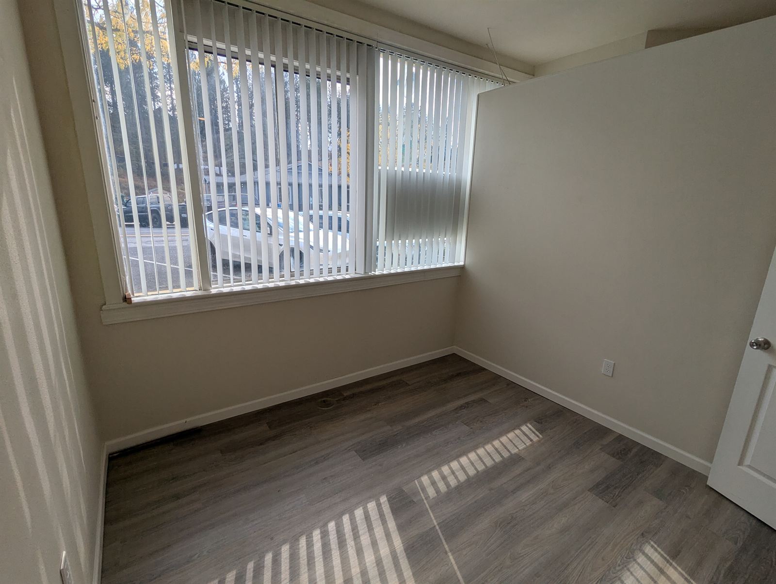Bright room with a large window and vertical blinds in Unit 2