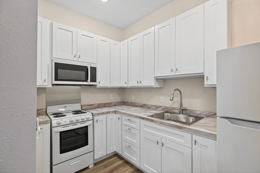 Unit 3 kitchen with white shaker cabinets, new appliances, and stone-look countertops